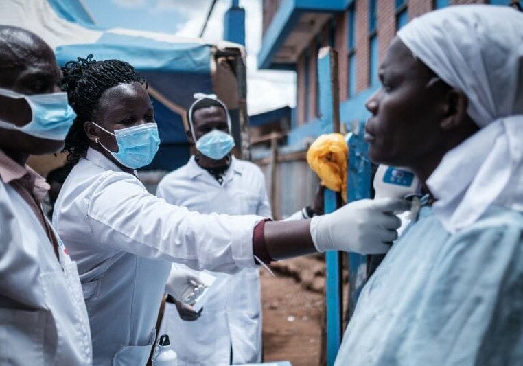 TOPSHOT - A staff of local NGO Shining Hope for Communities (SHOFCO) measures a woman's body tempreture as the NGO installs hand washing stations at the Kibera slum in Nairobi, on March 18, 2020. - African countries have been among the last to be hit by the global COVID-19 coronavirus epidemic but as cases rise, many nations are now taking strict measures to block the deadly illness. (Photo by Yasuyoshi CHIBA / AFP) (Photo by YASUYOSHI CHIBA/AFP via Getty Images)